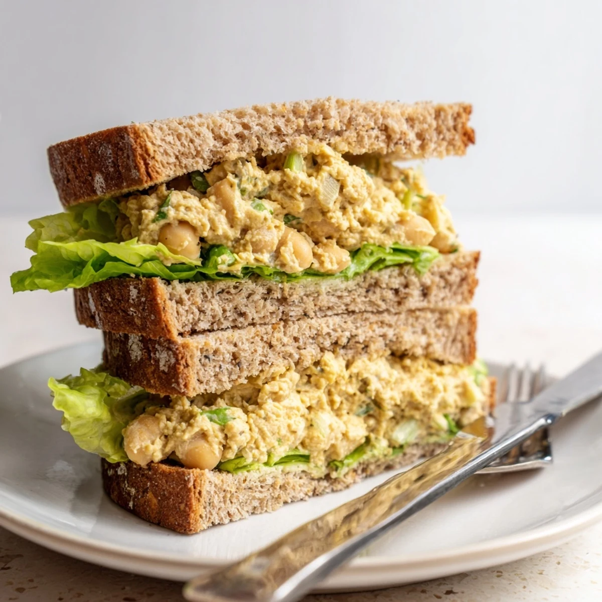 Creamy chickpea salad sandwich served on whole grain bread with crunchy celery.  