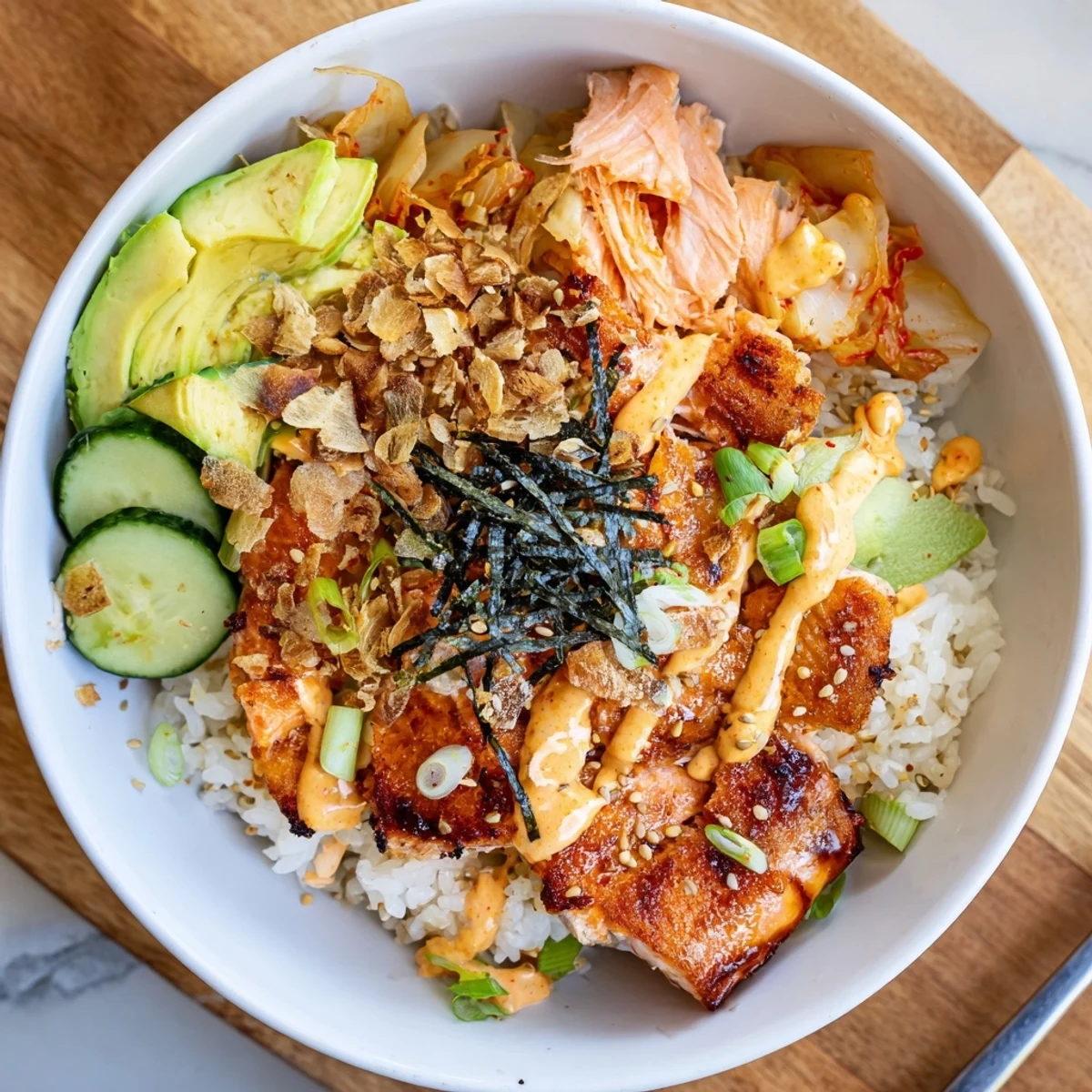 Crispy Salmon Rice Bowl topped with spicy mayo, kimchi, and fresh avocado slices.  