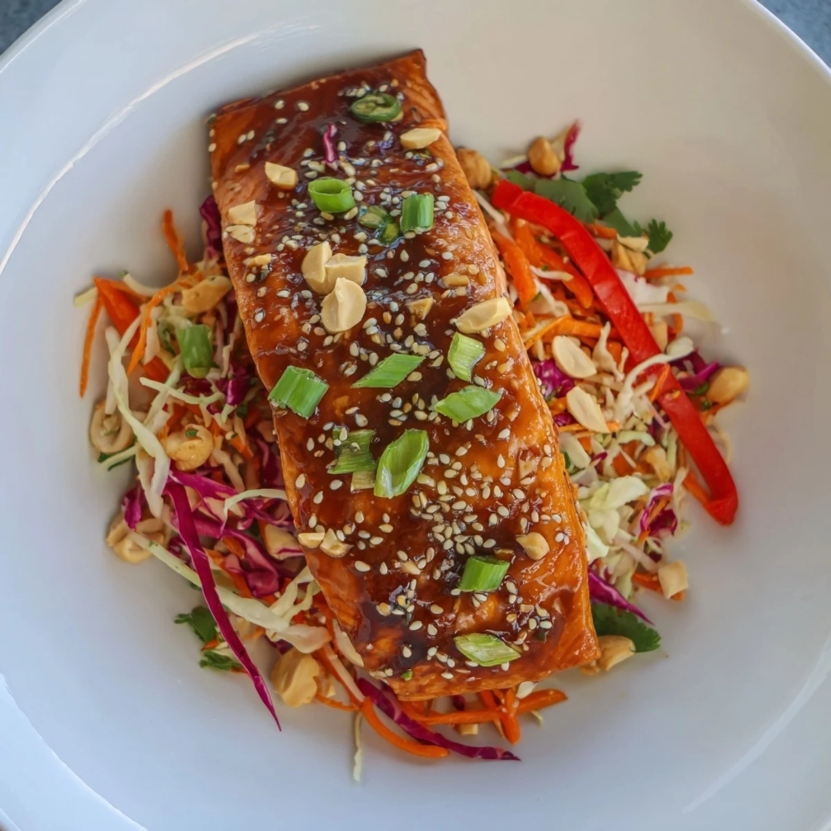 Savory teriyaki salmon glistening on a colorful Asian slaw bowl, ready for a delicious dinner.
