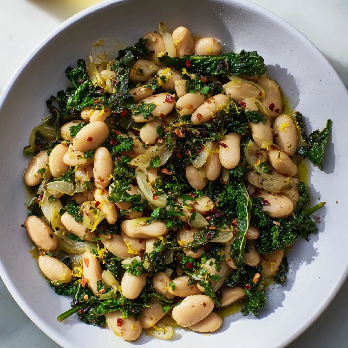 Close-up of rustic Garlicky Beans with Winter Greens, showcasing tender greens and creamy beans in a skillet.