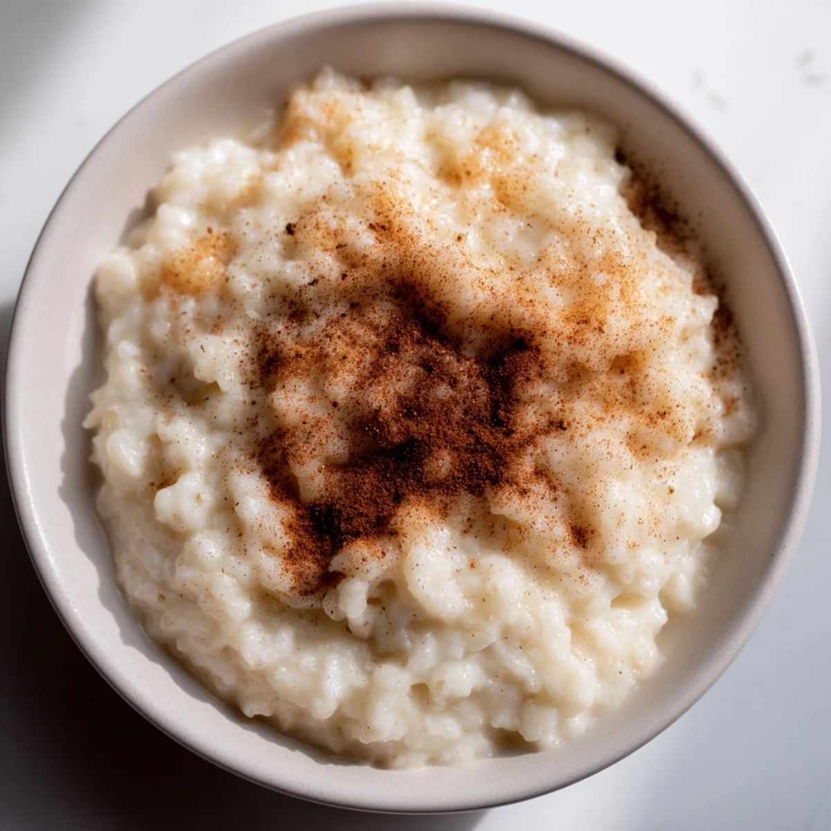 A warm bowl of creamy Rice Pudding with Leftover Rice, garnished with a sprinkle of cinnamon.