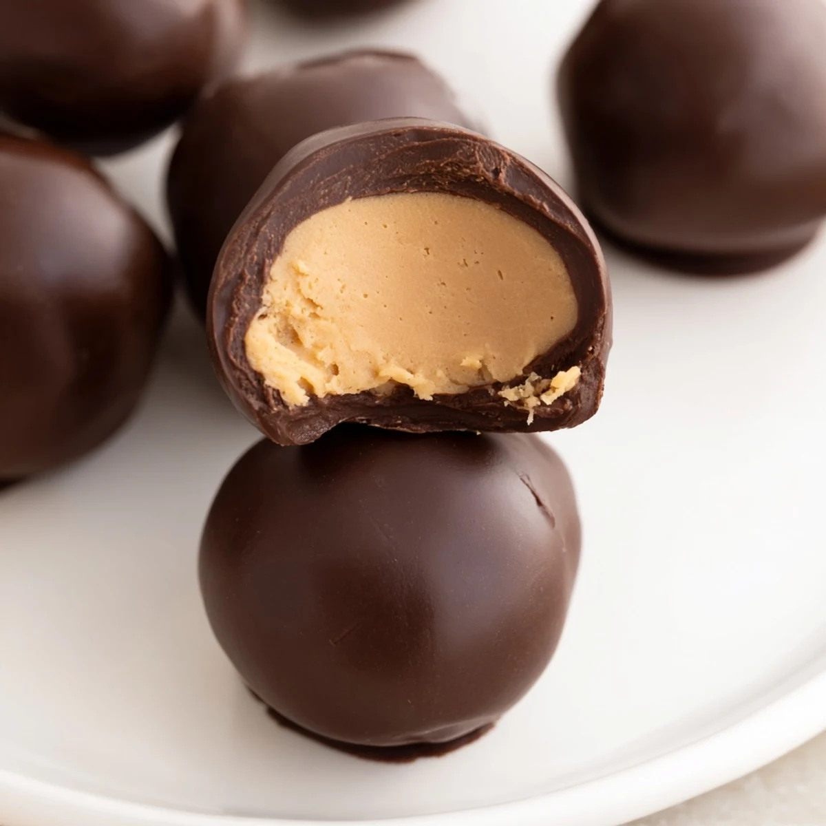 Creamy peanut butter buckeyes, partially dipped in chocolate, perfect for holiday dessert tables.