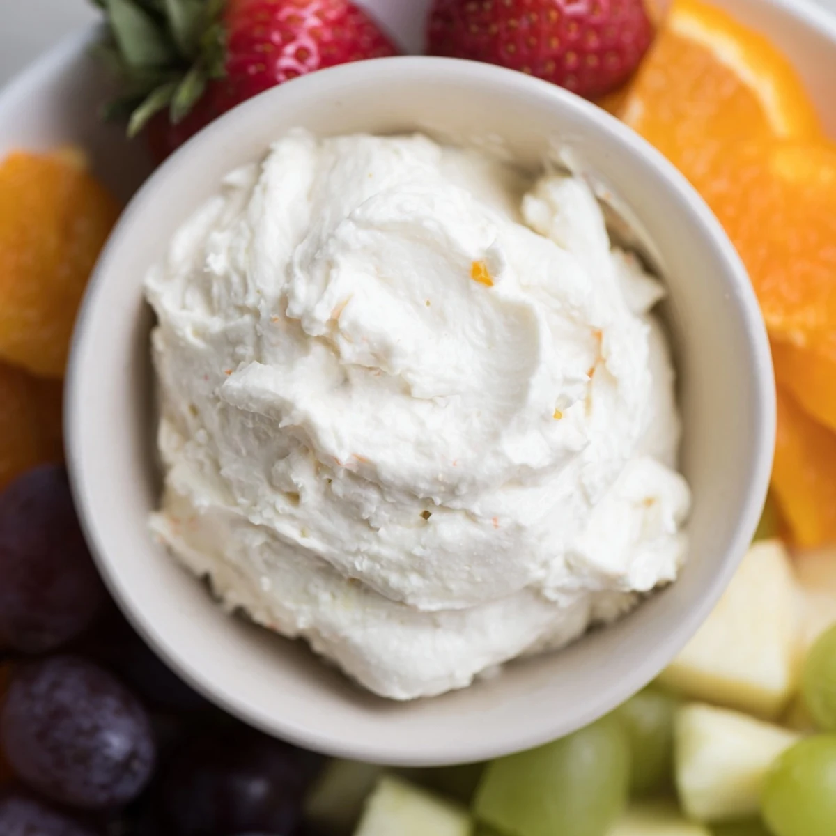 Homemade cream cheese fruit dip, served in a decorative bowl with refreshing fruit, is ready to be enjoyed.