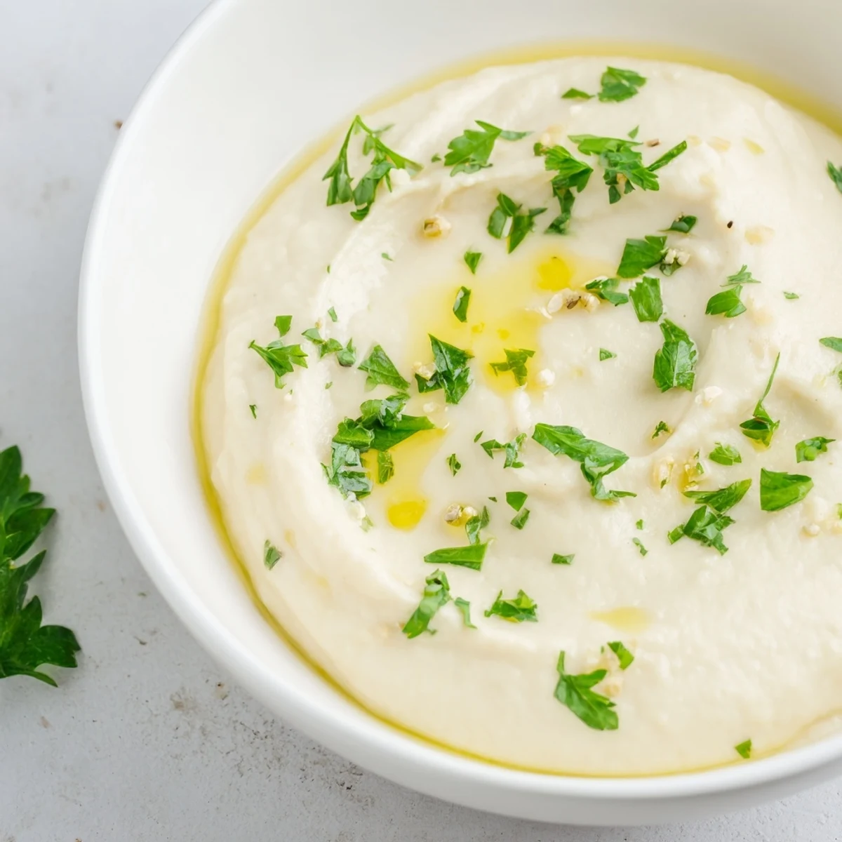 A close-up of smooth, blended White Bean Dip topped with fresh herbs, ready to serve.