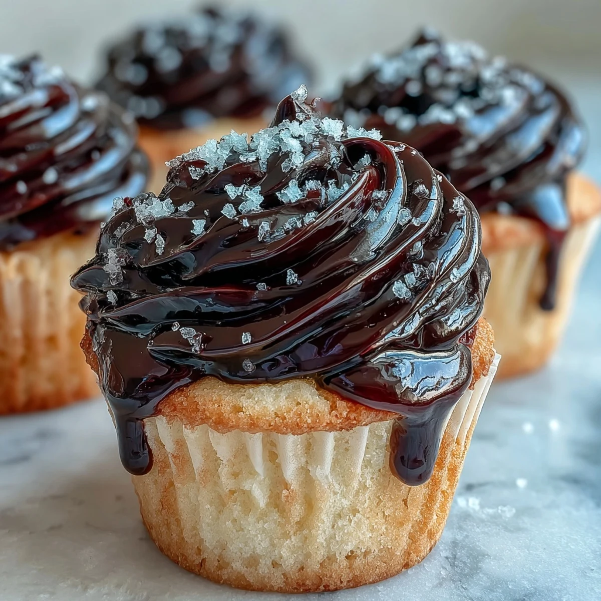 Freshly baked Olive Oil Cupcakes with rich black currant frosting are plated beside a steaming cup of Earl Grey tea.