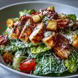 Close-up of a Romaine Caesar Bowl topped with shaved Parmesan and cherry tomatoes, ready to serve.  