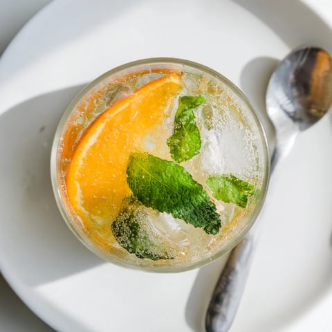 A vibrant probiotic soda mocktail topped with fresh mint and orange slices.  