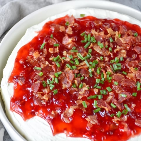 Easy Bacon Pepper Jelly Appetizer, topped with crispy bacon crumbles and served with crackers.