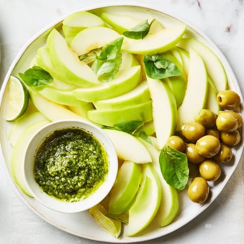 An Emerald City snack board overflowing with green apples, olives, and pesto for delightful appetizers.