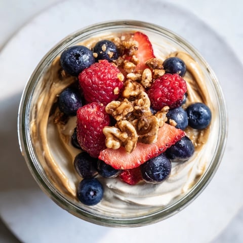 Cashew butter yogurt parfait layered with berries and granola, a creamy and refreshing breakfast.
