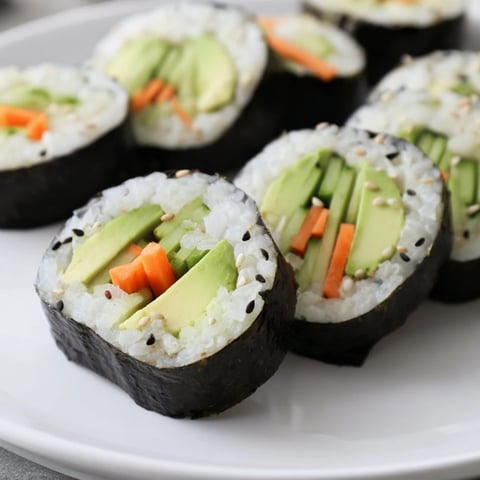 Fresh avocado cucumber sushi rolls, a healthy vegan meal arranged on a plate with dipping sauces.