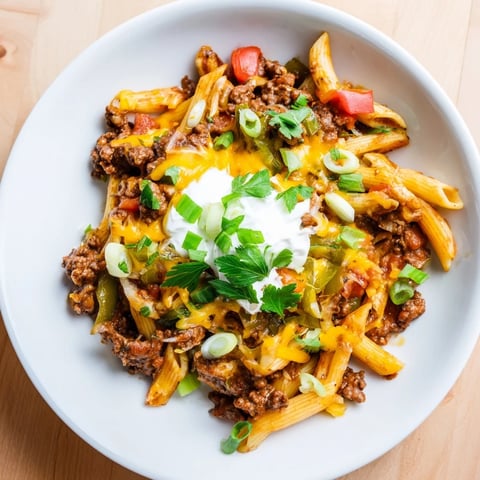 Steaming one-pot taco pasta, a cheesy comfort meal topped with fresh green onions and cilantro.