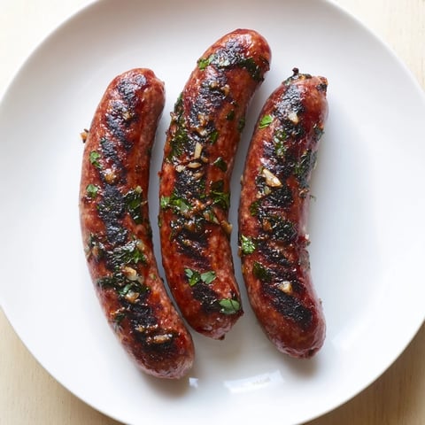 Grilled Tunisian Merguez sausage, browned and sizzling, offers savory flavors and aromatic spices.