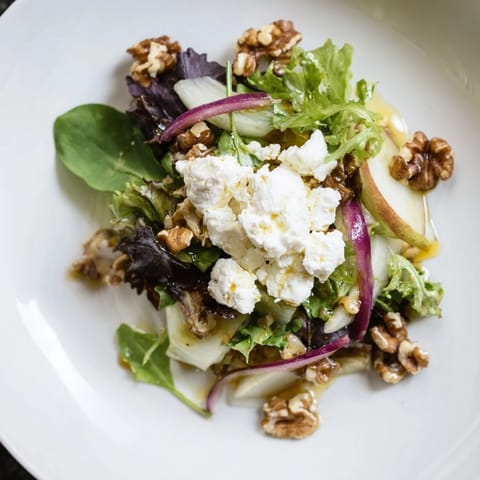 This Spiced Honey and Date Goat Cheese Salad boasts vibrant greens topped with spiced honey dressing.