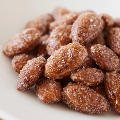 Warmly spiced cinnamon roasted almonds, glistening with a sugar coating, perfect as a snack.