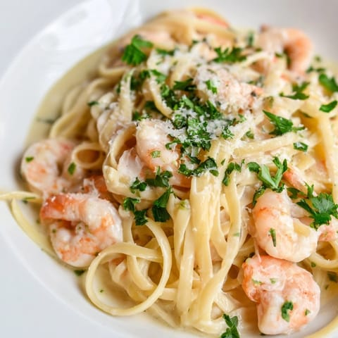 A close-up of Creamy Garlic Shrimp Pasta showing garlic-infused cream sauce clinging to noodles, garnished with fresh parsley.