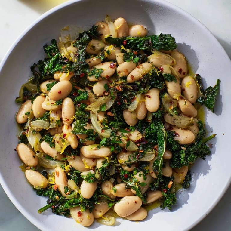 Close-up of rustic Garlicky Beans with Winter Greens, showcasing tender greens and creamy beans in a skillet.