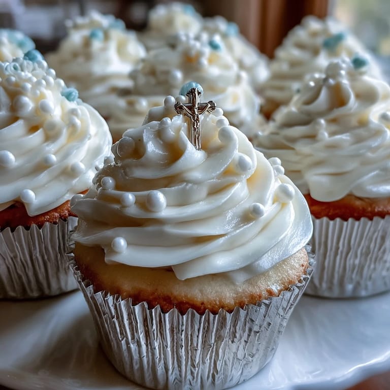 A batch of adorable mini First Communion cupcakes with creamy frosting and handmade fondant rosary accents, ideal for a religious milestone dessert table.