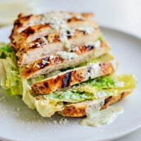 Golden-brown grilled chicken cutlets topped with crisp romaine lettuce and Parmesan cheese inside a toasted brioche bun.